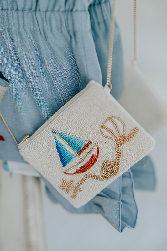 Beaded sailboat purse with red, blue, and gold details resting on white chair, styled with blue coastal outfit for girls
Close-up of nautical beaded crossbody bag featuring a colorful sailboat design, perfect for beach trips or summer gifting