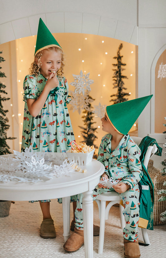 Child dressed in green Christmas pajamas with matching elf cone hat, standing in a winter-themed holiday setup
Boys festive holiday pajamas with playful Christmas print and felt elf hat, styled for family photos and Christmas morning
Toddler in Christmas sleepwear with reindeer and elf hat pattern, wearing slippers in cozy holiday backdrop with twinkle lights