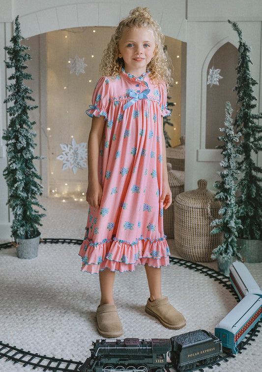 Girl wearing pink floral nightgown with ruffles and blue bows, styled for holiday photos or Christmas morning
Vintage-inspired pink girls nightgown with blue floral print, ruffled hem, and puff sleeves, perfect for winter lounging
Long pink holiday nightgown with double ruffle trim and blue satin bows, ideal for Christmas Eve or heirloom sleepwear