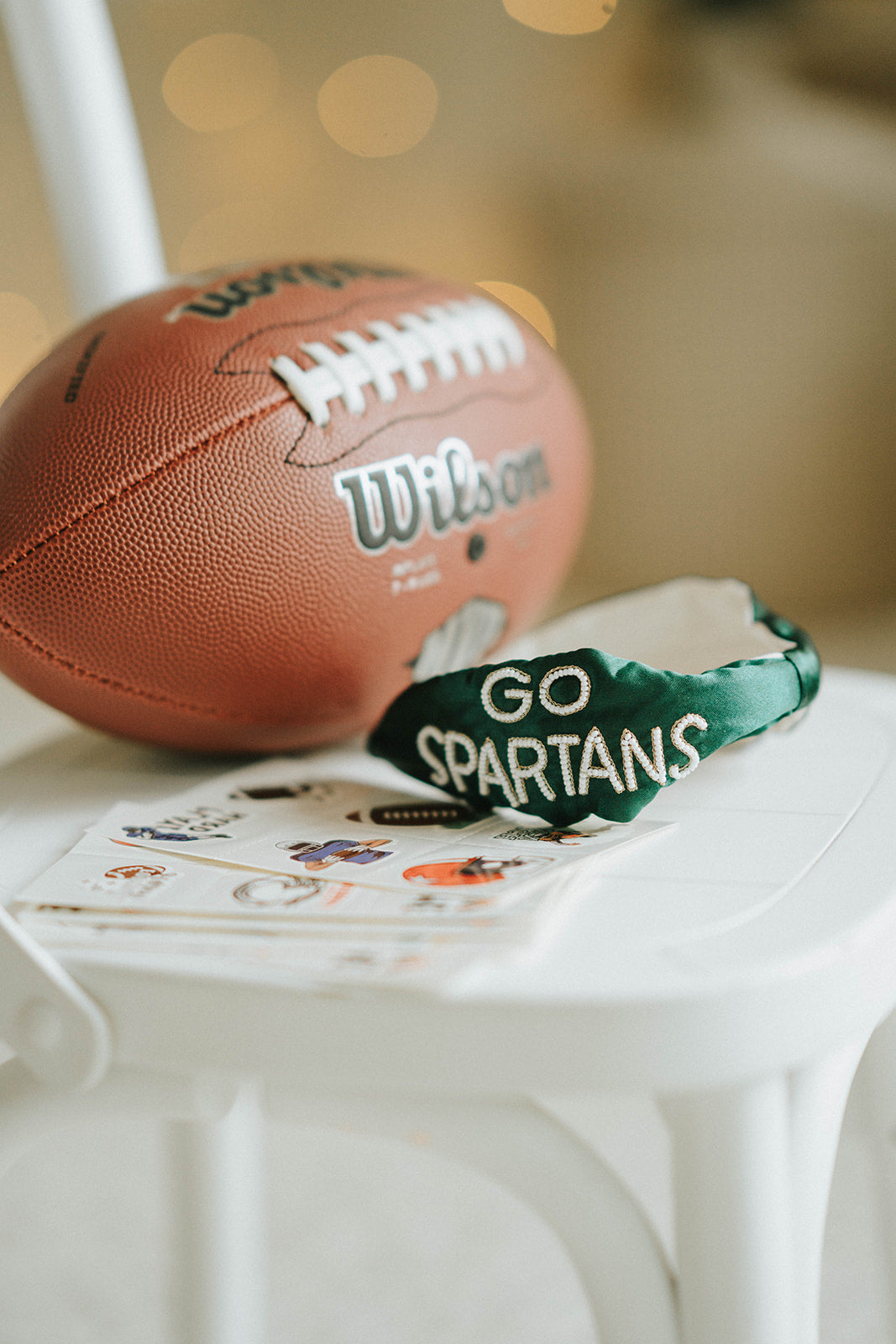 Girl wearing green “Go Spartans” headband holding a football on a grassy field at sunset, dressed in white tee and denim shorts
Child in team spirit outfit with green “Go Spartans” headband and football, perfect for game day or school pep rally
Little girl showing Spartan pride with beaded green headband and football, styled for fall sports or tailgate season
Girls football fan look with sparkly “Go Spartans” headband and casual outfit, standing in a field at golden hour