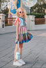 A vibrant metallic gown with colors of the rainbow. Pink flutter sleeves, tiered skirt perfect for twirling and a belted sash for that extra pizazz.