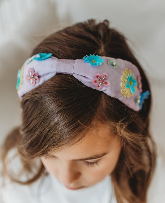 Our Rapunzel Headband is a lavender satin with multicolored flowers made out of different shaped sequins and beads. The flowers are teal, yellow, pink, purple and mint colored. This hair accessory is comfortable and designed for all day wear.