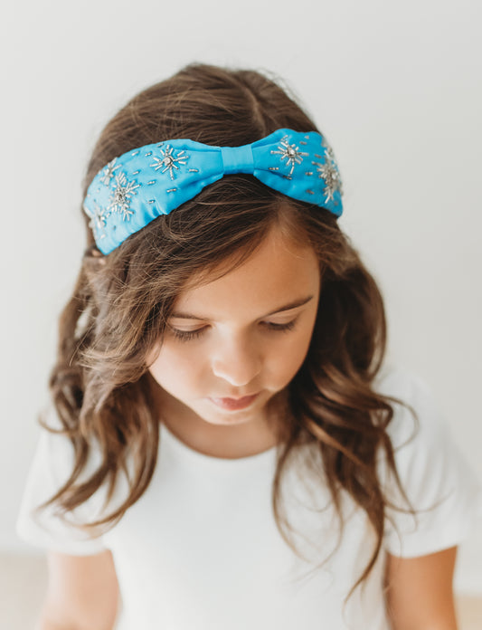A bright blue satin headband with snowflake crystal beadwork. Designed for all day comfort.