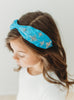 A bright blue satin headband with snowflake crystal beadwork. Designed for all day comfort.