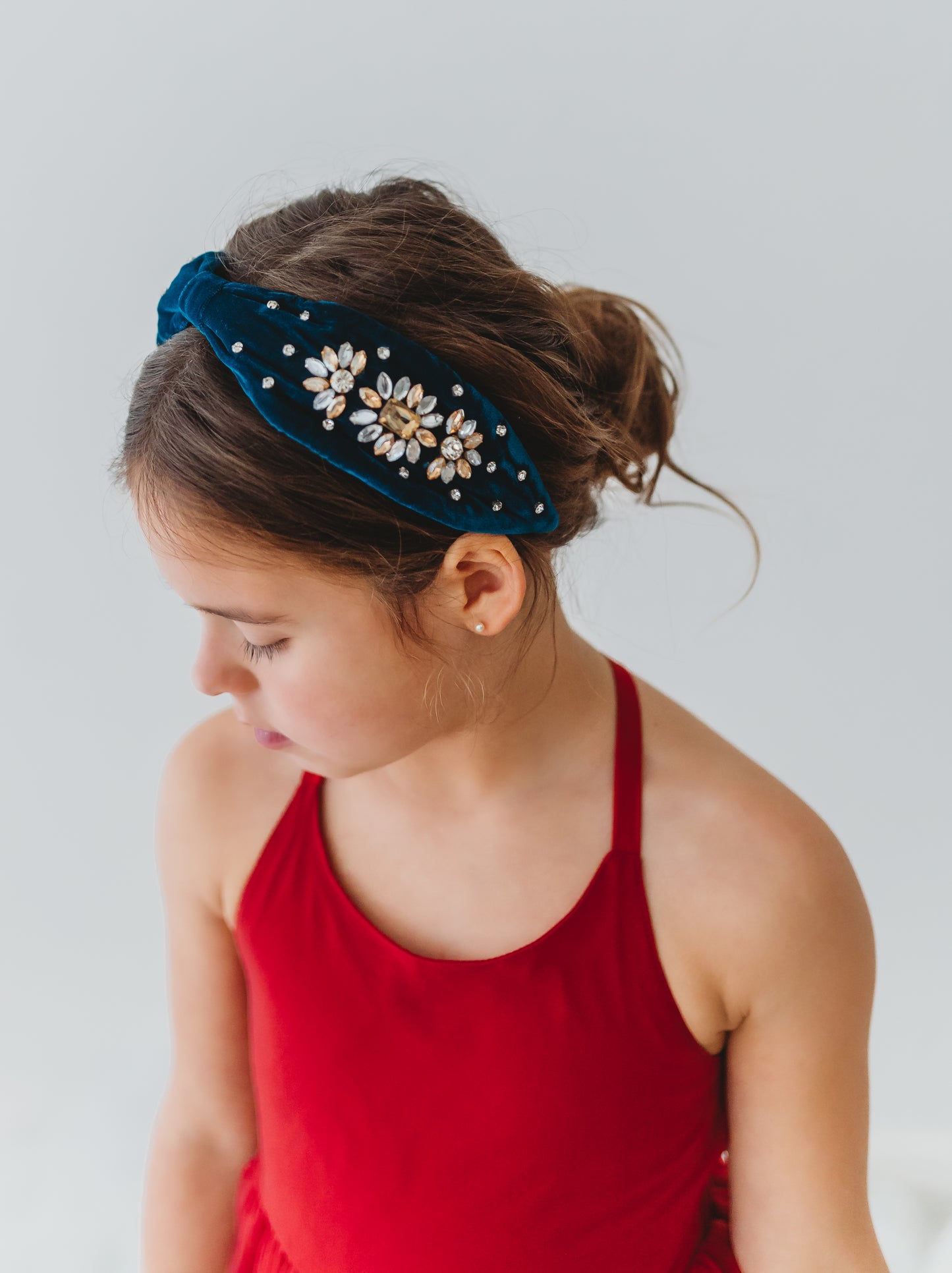The Courageous girl headband is a dark peacock teal velvet. It is designed for all day comfort. There are golden and silver crystals that adorn the sides. This show stopping hair accessory will make her feel like a princess!