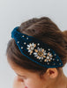 The Courageous girl headband is a dark peacock teal velvet. It is designed for all day comfort. There are golden and silver crystals that adorn the sides. This show stopping hair accessory will make her feel like a princess!