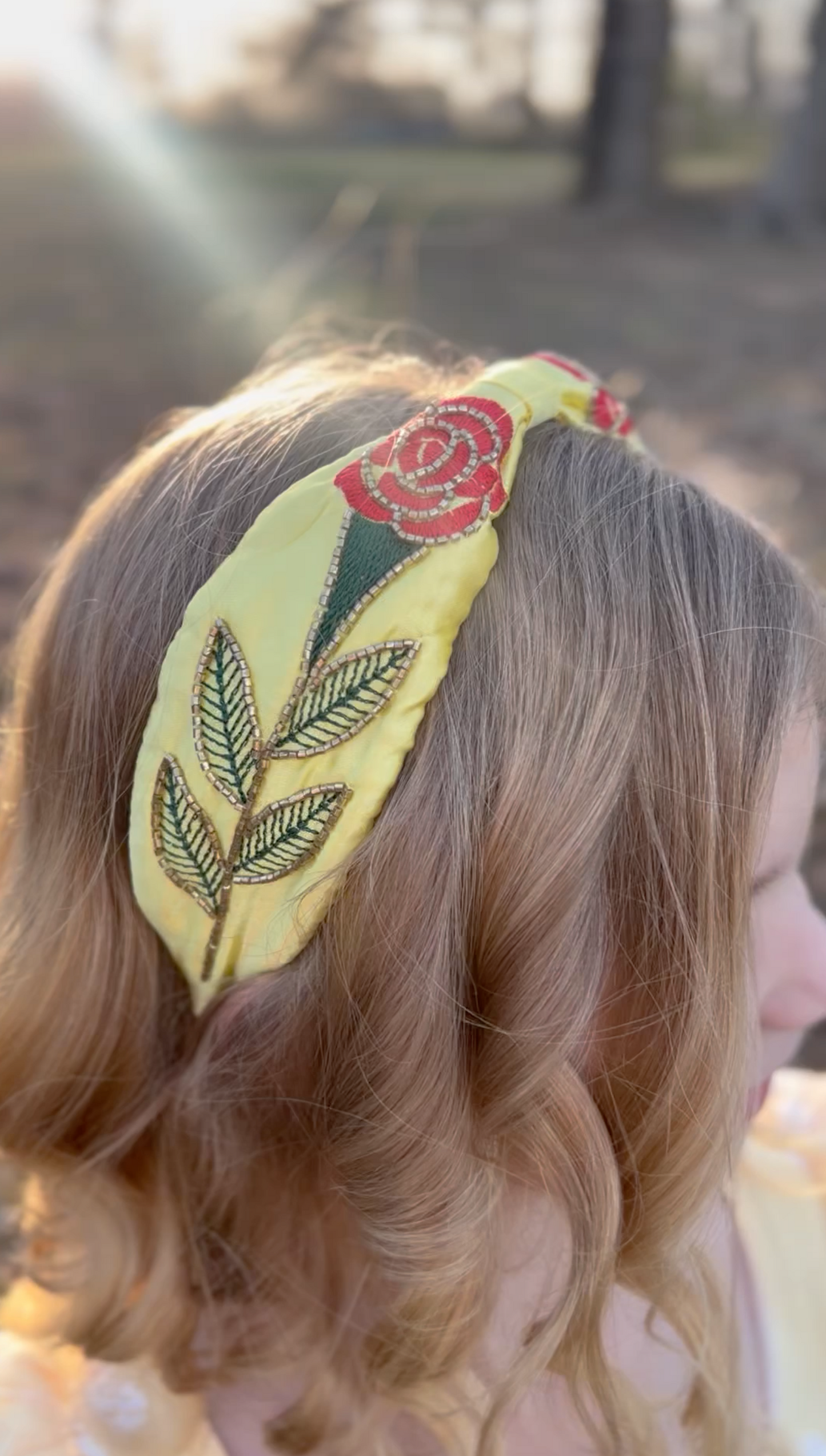 Our Red Rose Princess Headband is comfortable and designed for all day wear. The yellow satin has a red rose embroidered on each side. The rose, stem and leaves have beaded gold details.