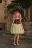 A young girl is wearing the Portrait Petite Twirl Length Snow White Gown. The gown is velvet blue and a light yellow skirt with a red ribbon criss cross accent on the bodice. The dress is sleeveless with a red and blue flutter ruffle on the top.