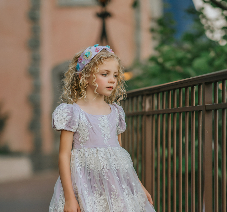 Our Rapunzel Headband is a lavender satin with multicolored flowers made out of different shaped sequins and beads. The flowers are teal, yellow, pink, purple and mint colored. This hair accessory is comfortable and designed for all day wear.