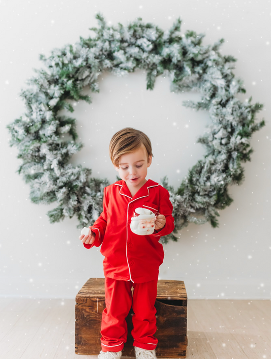 A young child is dressed in the buttery soft Unisex Pj's in Red from our Christmas Lounge Collection. The true Christmas red pajamas have a classic design. They are piped with white trim. The 2 piece pj set is perfect for photos and warm cozy holiday cheer.