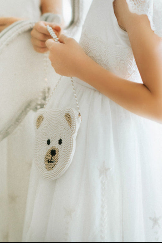 Girls teddy bear crossbody bag with pearl beading, ideal accessory for flower girls, dress-up, or special occasion outfits
Beaded bear face purse with pearls and gold accents, hanging from a white embroidered gown for a formal or dressy look