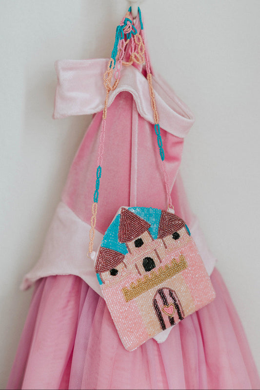 Beaded pink castle purse hanging on a pink princess dress, perfect for little girls’ dress-up and birthday gift ideas