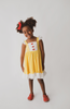 A young girl is wearing our Original Red Rose Twirl Dress from the Princess Twirl Collection. The sleeveless yellow dress features white ruffled trim and three red roses down the front. The sunny yellow dress provides a perfect princess twirl and soft comfortable cotton fabric.