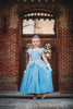 A young girl stands in a light blue gown. The chiffon puff sleeves lead into a light blue lace bodice. There is a small chiffon bustle ruffle over a stretch velour skirt. The skirt is lined with tulle and cotton for fullness.
