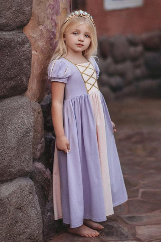 A young girl is wearing the light purple Rapunzel Maxi Dress. The lavender princess dress features puffed sleeves and a crisscrossed gold trim. The light pink panel adorns the middle front and back.