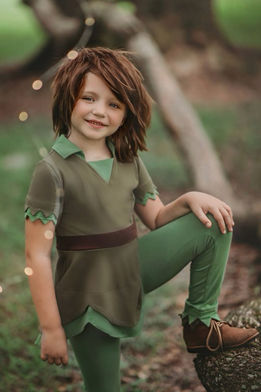 A young child is wearing an earthy green tunic with leaf green collar.  The short sleeves have a double layer detail. The bottom hem is a handkerchief cut. 