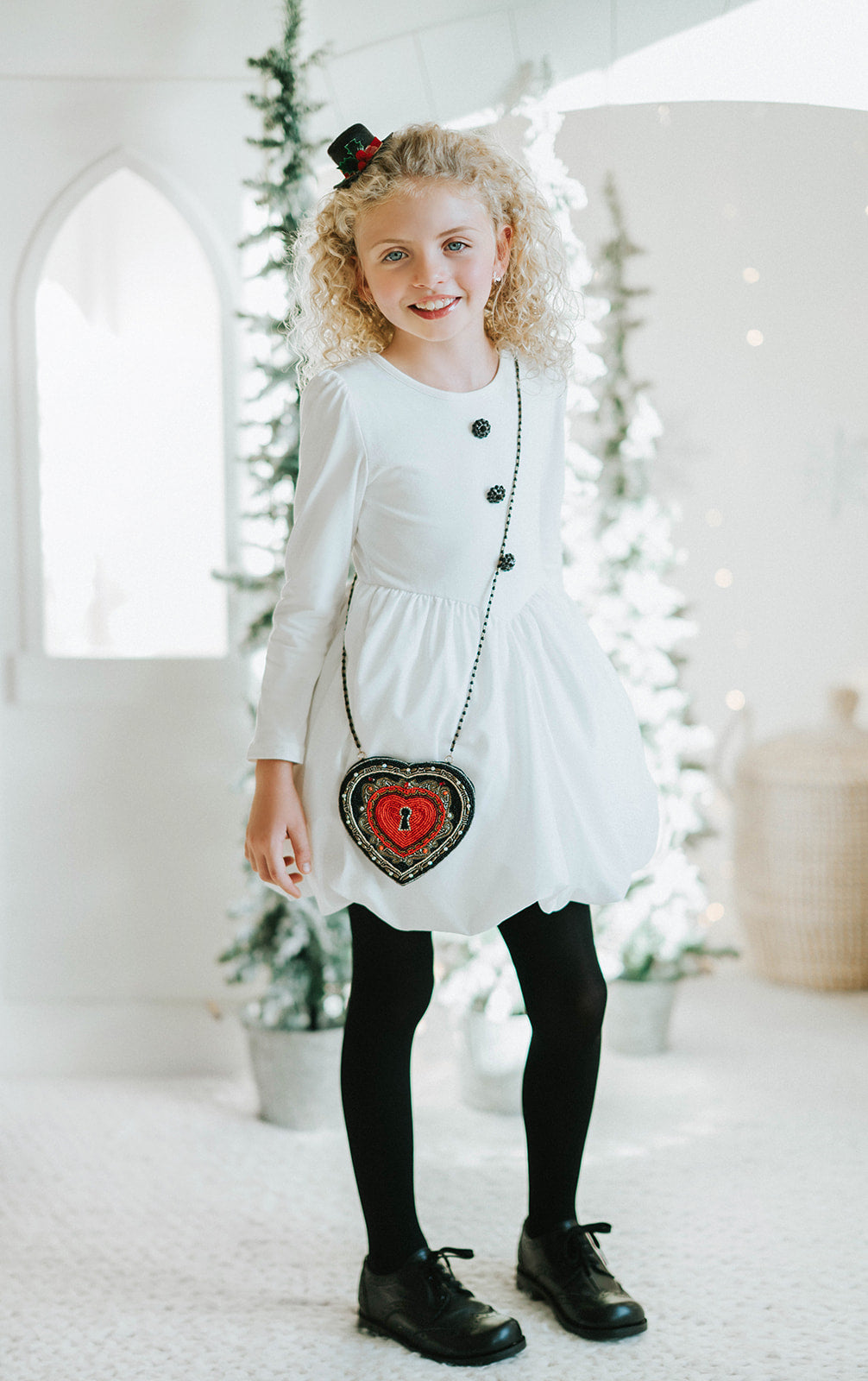 Beaded heart purse with red and black design, keyhole detail, and intricate gold stitching, styled with a white dress and blue tartan scarf for a fairytale holiday accessory look.

Gothic-inspired red heart handbag with keyhole motif and beadwork, worn by girl in winter outfit, perfect for Valentine’s Day, fairytale fashion, or themed photoshoots.

Close-up of a heart-shaped beaded purse with ornate swirls, pearl accents, and a romantic keyhole center, styled for girls or women who love storybook and fantas
