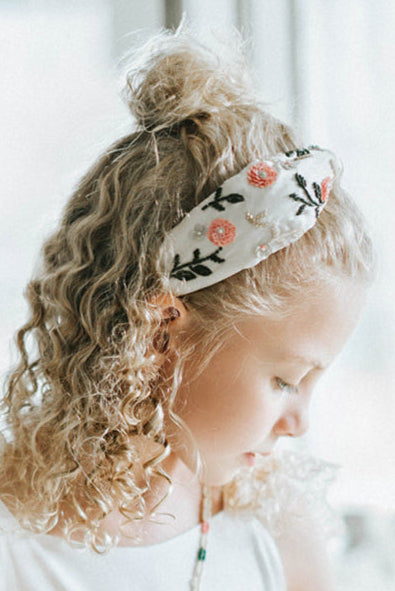 Beaded flower girl handbag with floral design and gold lettering on a young girl in white dress, perfect for weddings