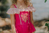 Girl wearing pink princess-inspired swimsuit with gold embroidery and ruffle off-shoulder detail, posing barefoot by the water

Girls royal-themed pink and gold one-piece swimsuit with peplum skirt, styled with ruffled straps and heart sunglasses

Princess bathing suit for girls in hot pink with gold lace trim and off-shoulder ruffles, perfect for summer dress-up swimwear