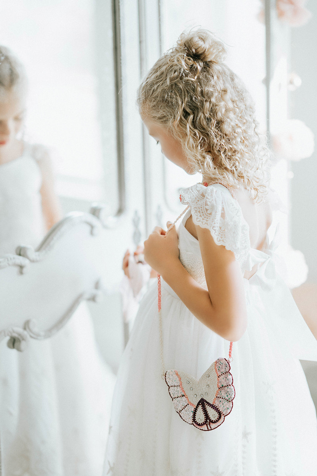 Girls’ butterfly-shaped beaded purse with sequin wings and pink strap, styled with an elegant white dress

Delicate butterfly crossbody purse with beaded wings and sparkle detail, perfect for dress-up or special occasions

Iridescent butterfly beaded bag hanging from a girl's shoulder, styled with embroidered white gown

Whimsical sequin butterfly purse for girls with pink and pearl beading, ideal for weddings or birthday dress-up