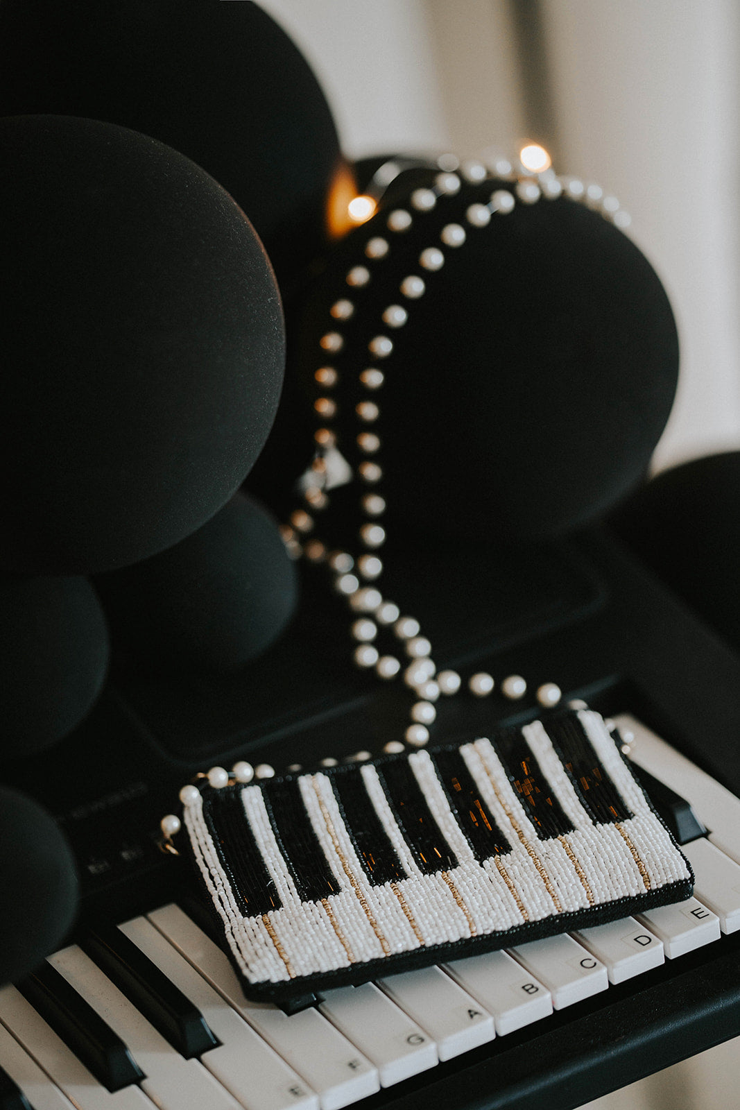 Hand-beaded black and white piano clutch with gold accents and pearl strap, styled on a keyboard for musicians, concert accessories, or music-themed gifts.

Elegant piano key beaded clutch purse with pearl shoulder strap, featuring black and white seed beads and gold shimmer, ideal for recitals or evening events.

Black and white piano beaded purse resting on piano keys, with pearl crossbody strap, styled for music lovers and formal holiday or recital nights.