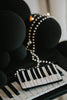 Hand-beaded black and white piano clutch with gold accents and pearl strap, styled on a keyboard for musicians, concert accessories, or music-themed gifts.

Elegant piano key beaded clutch purse with pearl shoulder strap, featuring black and white seed beads and gold shimmer, ideal for recitals or evening events.

Black and white piano beaded purse resting on piano keys, with pearl crossbody strap, styled for music lovers and formal holiday or recital nights.