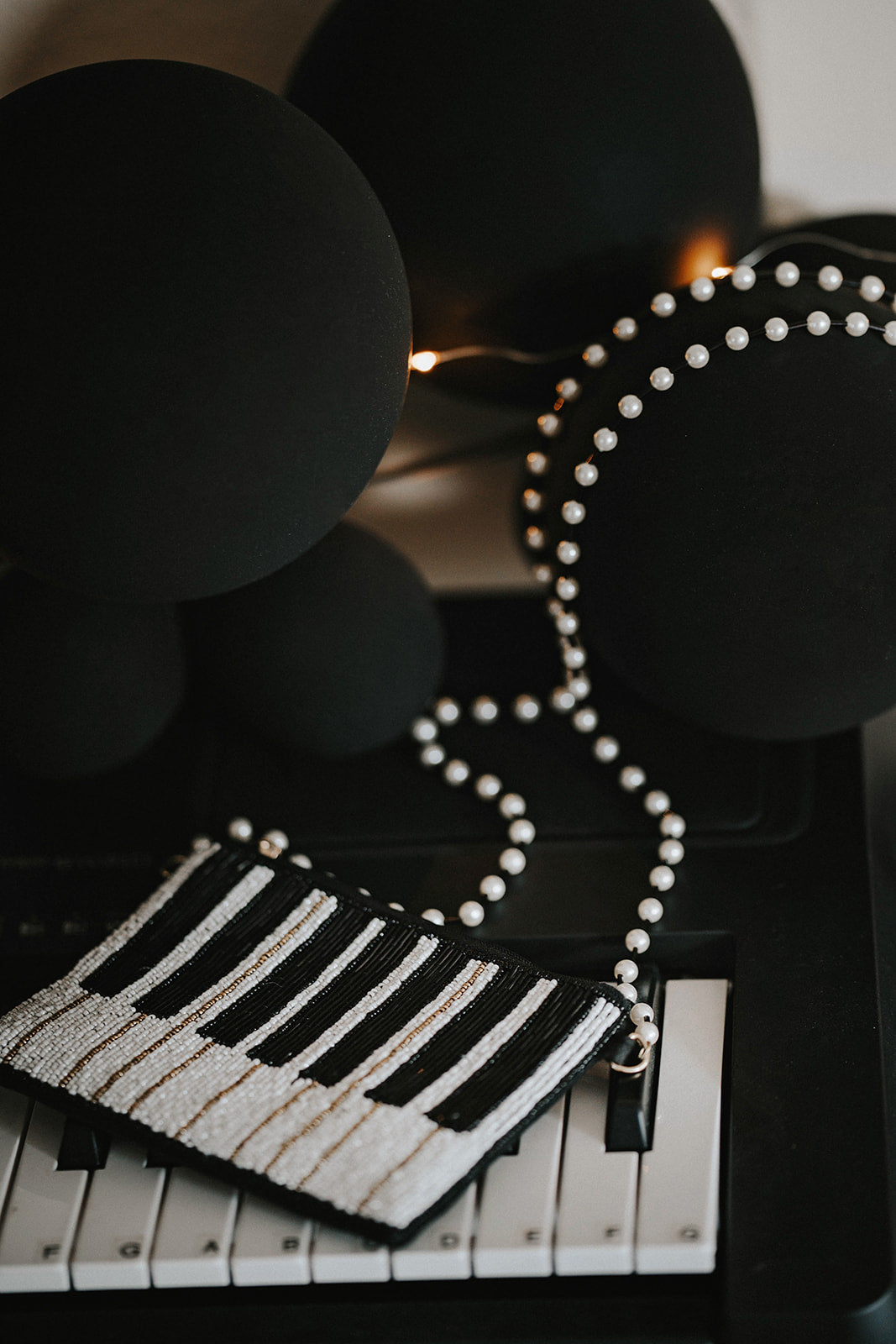 Hand-beaded black and white piano clutch with gold accents and pearl strap, styled on a keyboard for musicians, concert accessories, or music-themed gifts.

Elegant piano key beaded clutch purse with pearl shoulder strap, featuring black and white seed beads and gold shimmer, ideal for recitals or evening events.

Black and white piano beaded purse resting on piano keys, with pearl crossbody strap, styled for music lovers and formal holiday or recital nights.