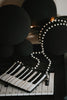 Hand-beaded black and white piano clutch with gold accents and pearl strap, styled on a keyboard for musicians, concert accessories, or music-themed gifts.

Elegant piano key beaded clutch purse with pearl shoulder strap, featuring black and white seed beads and gold shimmer, ideal for recitals or evening events.

Black and white piano beaded purse resting on piano keys, with pearl crossbody strap, styled for music lovers and formal holiday or recital nights.