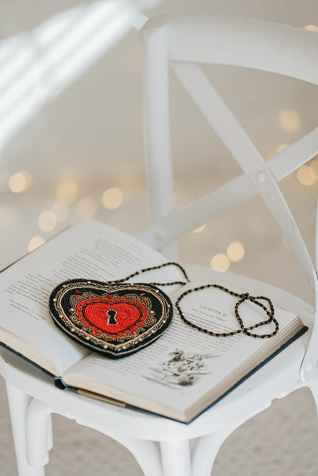 Beaded heart purse with red and black design, keyhole detail, and intricate gold stitching, styled with a white dress and blue tartan scarf for a fairytale holiday accessory look.

Gothic-inspired red heart handbag with keyhole motif and beadwork, worn by girl in winter outfit, perfect for Valentine’s Day, fairytale fashion, or themed photoshoots.

Close-up of a heart-shaped beaded purse with ornate swirls, pearl accents, and a romantic keyhole center, styled for girls or women who love storybook and fantas