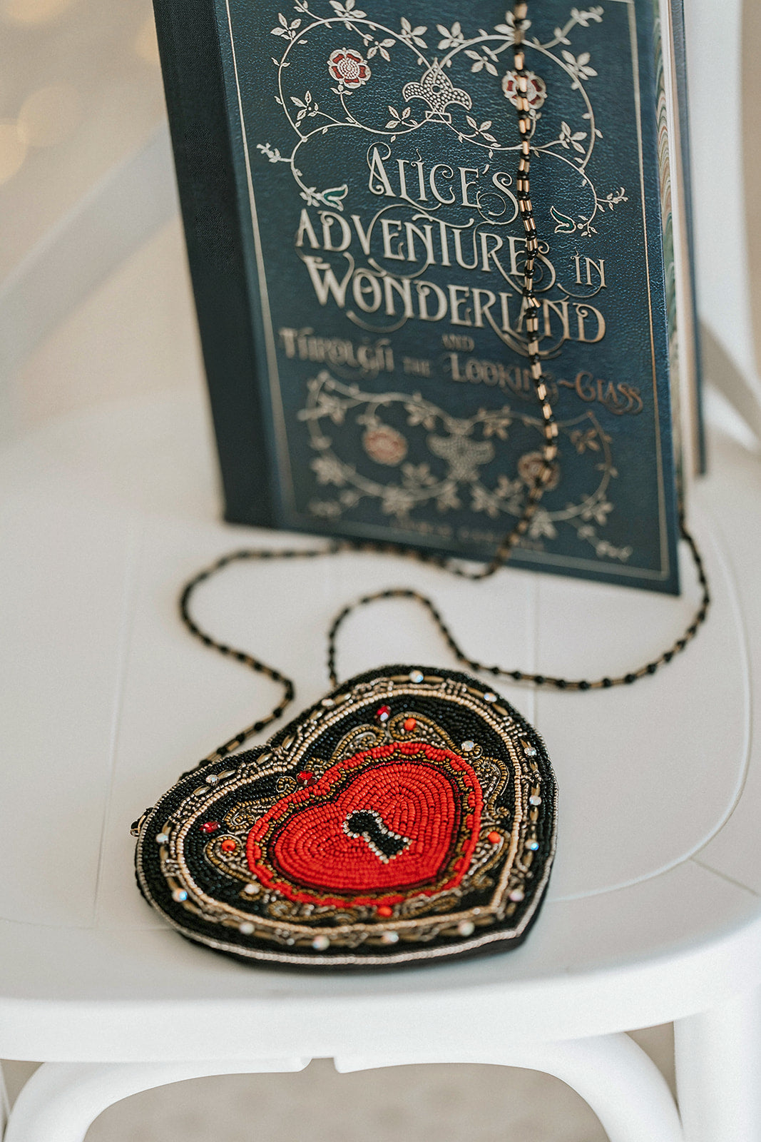 Beaded heart purse with red and black design, keyhole detail, and intricate gold stitching, styled with a white dress and blue tartan scarf for a fairytale holiday accessory look.

Gothic-inspired red heart handbag with keyhole motif and beadwork, worn by girl in winter outfit, perfect for Valentine’s Day, fairytale fashion, or themed photoshoots.

Close-up of a heart-shaped beaded purse with ornate swirls, pearl accents, and a romantic keyhole center, styled for girls or women who love storybook and fantas