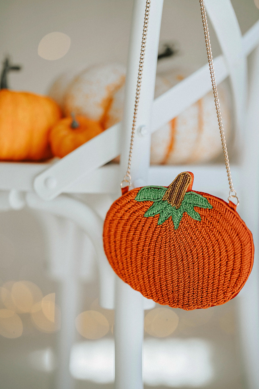 Beaded pumpkin-shaped purse with orange seed beads, green leaf detail, and gold chain strap, styled on a white chair with mini pumpkins for fall or Halloween accessories.

Hand-beaded pumpkin purse with green leaves and gold chain, perfect autumn handbag for Halloween outfits, Thanksgiving events, or cozy fall accessories.

Fall-themed pumpkin crossbody bag with beaded design and gold strap, styled with mini pumpkins on a white chair, ideal for spooky season or Thanksgiving gifting.