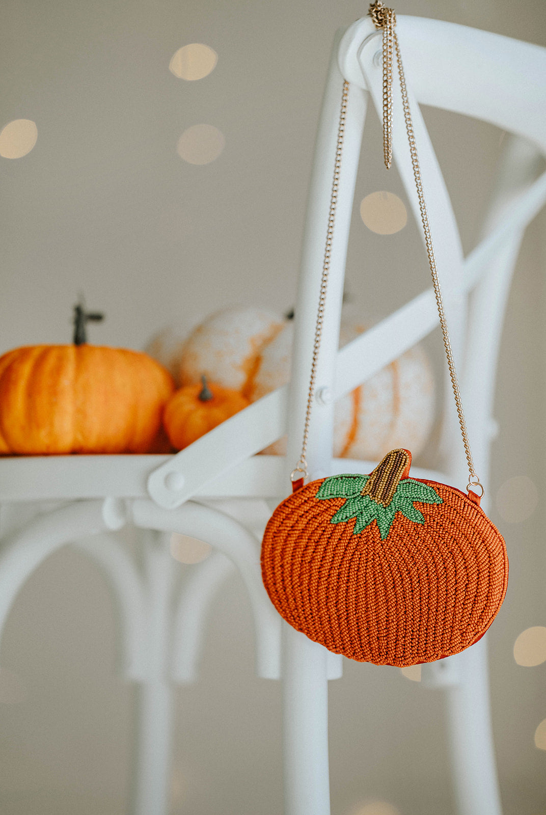 Beaded pumpkin-shaped purse with orange seed beads, green leaf detail, and gold chain strap, styled on a white chair with mini pumpkins for fall or Halloween accessories.

Hand-beaded pumpkin purse with green leaves and gold chain, perfect autumn handbag for Halloween outfits, Thanksgiving events, or cozy fall accessories.

Fall-themed pumpkin crossbody bag with beaded design and gold strap, styled with mini pumpkins on a white chair, ideal for spooky season or Thanksgiving gifting.