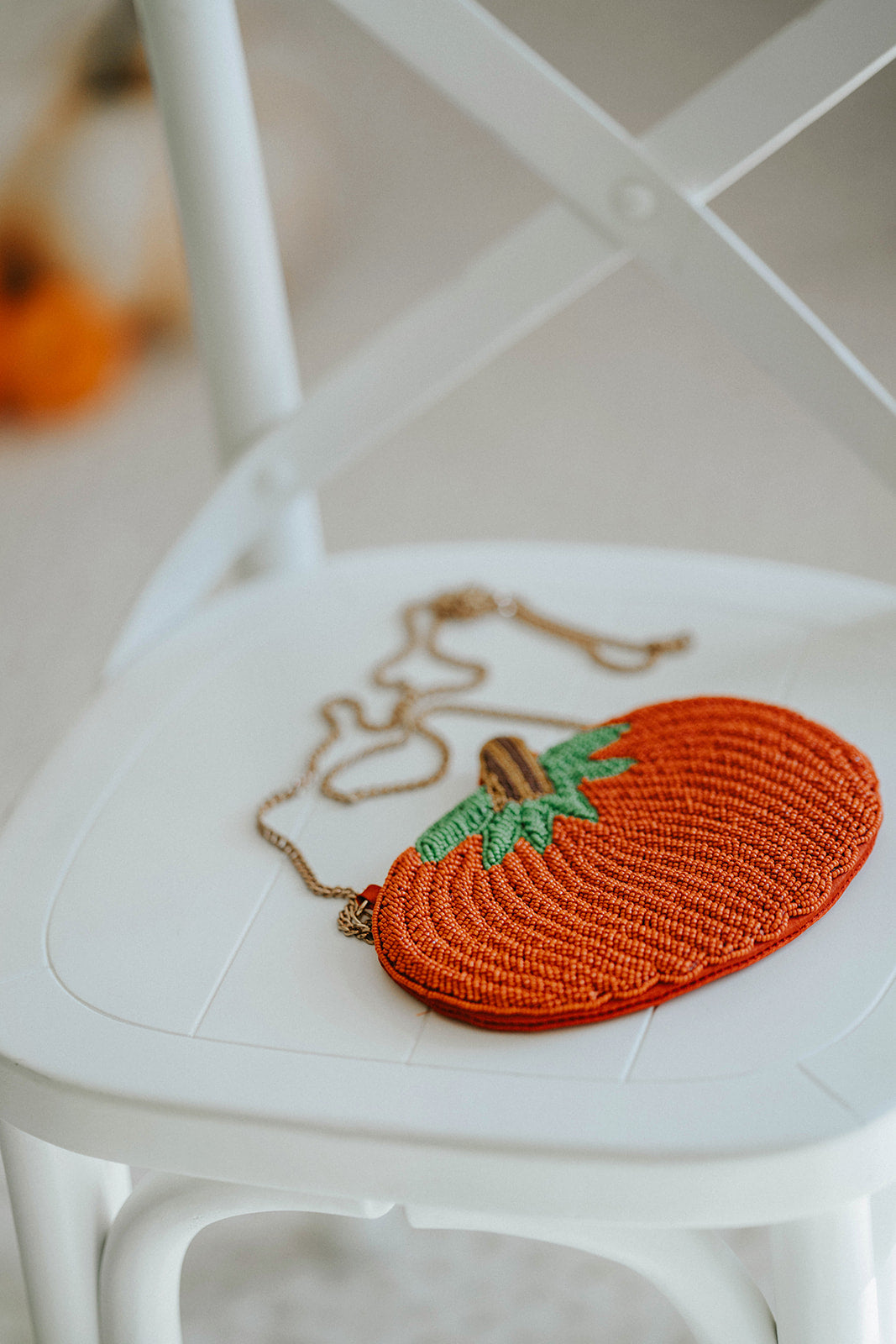 Beaded pumpkin-shaped purse with orange seed beads, green leaf detail, and gold chain strap, styled on a white chair with mini pumpkins for fall or Halloween accessories.

Hand-beaded pumpkin purse with green leaves and gold chain, perfect autumn handbag for Halloween outfits, Thanksgiving events, or cozy fall accessories.

Fall-themed pumpkin crossbody bag with beaded design and gold strap, styled with mini pumpkins on a white chair, ideal for spooky season or Thanksgiving gifting.