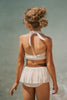 Boho-inspired cream girls swimsuit with wrap detail and side draping, styled for beach photos or summer vacation

Toddler to tween girl in goddess-style cream bathing suit with halter neckline and high-waisted bottoms, standing on the shore

Girls neutral swimwear set featuring wrap halter top and soft mesh skirt, perfect for boho beachwear or summer shoots
