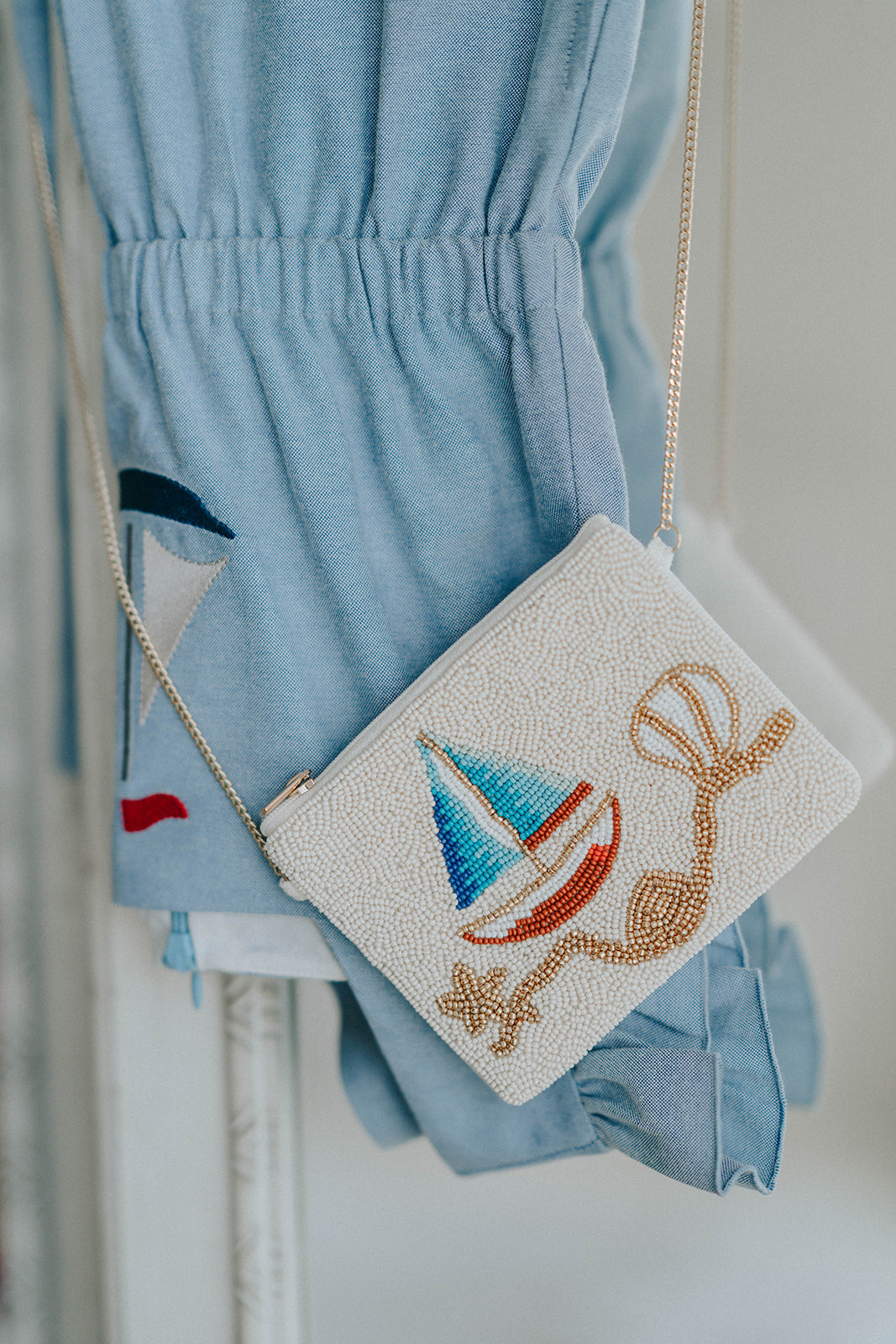 Beaded sailboat purse with red, blue, and gold details resting on white chair, styled with blue coastal outfit for girls

Close-up of nautical beaded crossbody bag featuring a colorful sailboat design, perfect for beach trips or summer gifting