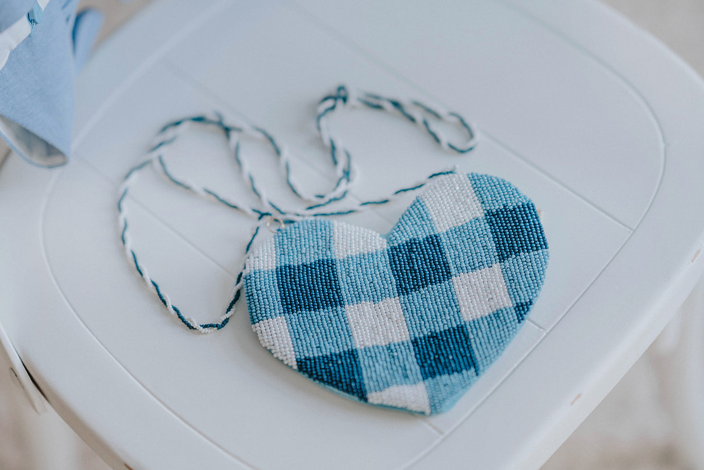 Close-up of heart-shaped beaded crossbody bag in blue buffalo plaid, styled for spring, Valentine’s Day, or dress-up

Blue gingham heart purse made with delicate beads and braided strap, ideal for toddler gift or cottagecore accessory

Beaded blue and white heart-shaped purse with crossbody strap, styled as a girls fashion or holiday photo prop

Girls’ gingham beaded purse in heart shape, featuring blue and ivory plaid design with braided handle for toddler or child