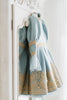 Victorian-inspired blue girls dress with gold embroidery, puff sleeves, and pearl buttons, perfect for birthdays or special occasions

Elegant heirloom girls dress in dusty blue with gold lace trim and tulle layers, hanging on ornate vintage-style mirror

Long sleeve blue and gold embroidered holiday dress for girls, featuring pearl buttons and layered tulle hem