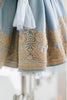 Victorian-inspired blue girls dress with gold embroidery, puff sleeves, and pearl buttons, perfect for birthdays or special occasions

Elegant heirloom girls dress in dusty blue with gold lace trim and tulle layers, hanging on ornate vintage-style mirror

Long sleeve blue and gold embroidered holiday dress for girls, featuring pearl buttons and layered tulle hem