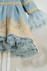 Elegant heirloom girls dress in dusty blue with gold lace trim and tulle layers, hanging on ornate vintage-style mirror

Long sleeve blue and gold embroidered holiday dress for girls, featuring pearl buttons and layered tulle hem

Girls vintage-style formal gown in soft blue with gold lace and flounce sleeves, ideal for portraits or weddings

Classic blue heirloom dress for toddlers and girls with ornate embroidery and pearl detailing, styled for a timeless photo shoot