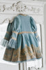 Victorian-inspired blue girls dress with gold embroidery, puff sleeves, and pearl buttons, perfect for birthdays or special occasions

Elegant heirloom girls dress in dusty blue with gold lace trim and tulle layers, hanging on ornate vintage-style mirror

Long sleeve blue and gold embroidered holiday dress for girls, featuring pearl buttons and layered tulle hem