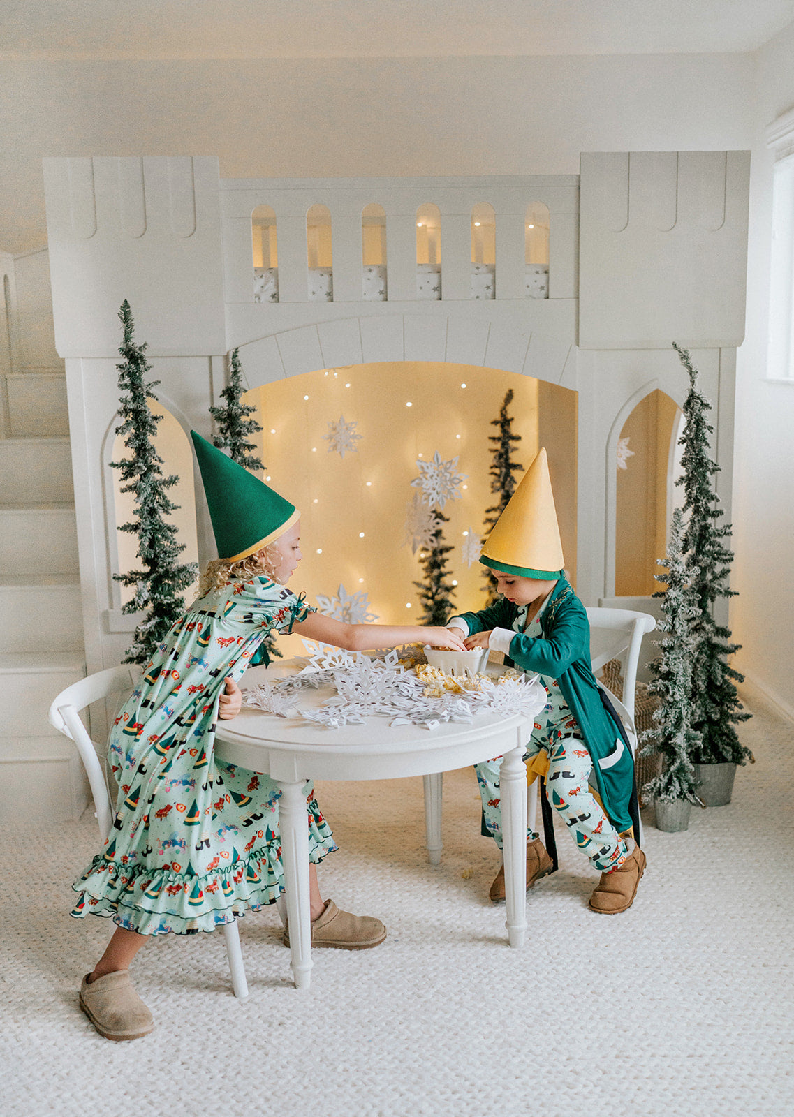 Child dressed in green Christmas pajamas with matching elf cone hat, standing in a winter-themed holiday setup

Boys festive holiday pajamas with playful Christmas print and felt elf hat, styled for family photos and Christmas morning

Toddler in Christmas sleepwear with reindeer and elf hat pattern, wearing slippers in cozy holiday backdrop with twinkle lights