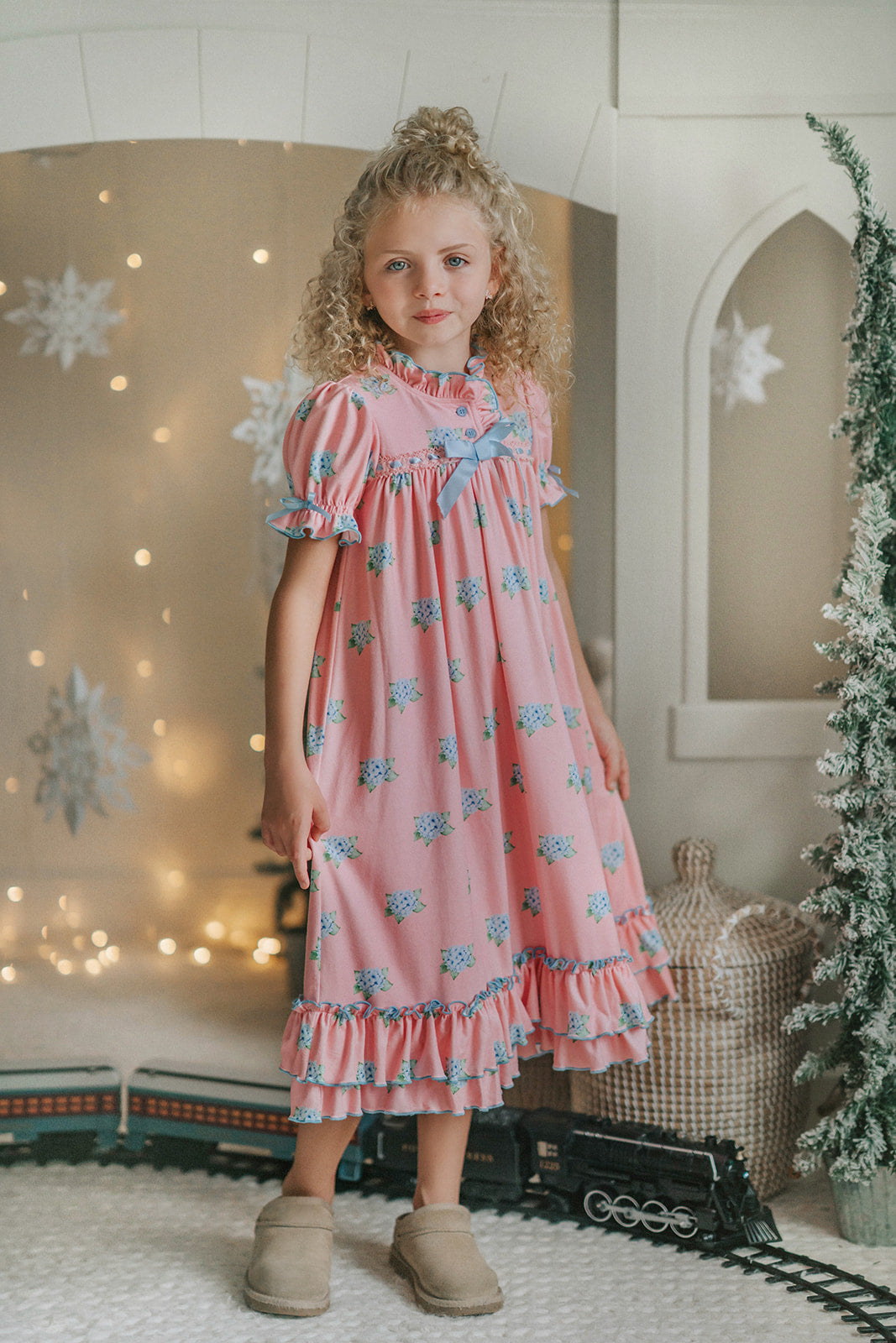 Girl wearing pink floral nightgown with ruffles and blue bows, styled for holiday photos or Christmas morning

Vintage-inspired pink girls nightgown with blue floral print, ruffled hem, and puff sleeves, perfect for winter lounging

Long pink holiday nightgown with double ruffle trim and blue satin bows, ideal for Christmas Eve or heirloom sleepwear