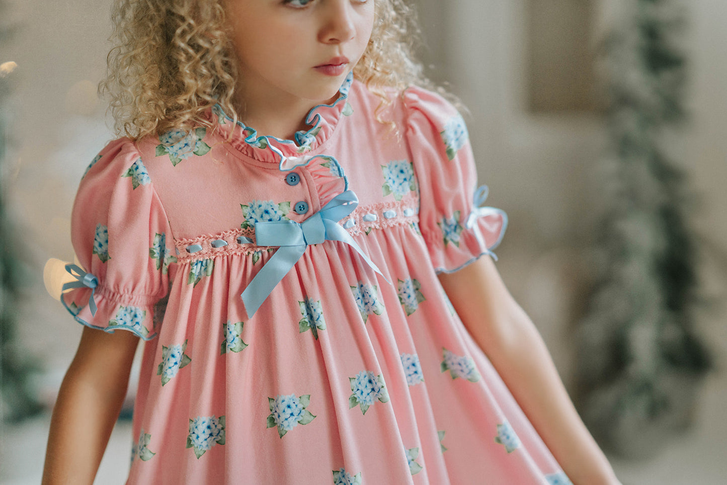 Girl wearing pink floral nightgown with ruffles and blue bows, styled for holiday photos or Christmas morning

Vintage-inspired pink girls nightgown with blue floral print, ruffled hem, and puff sleeves, perfect for winter lounging

Long pink holiday nightgown with double ruffle trim and blue satin bows, ideal for Christmas Eve or heirloom sleepwear