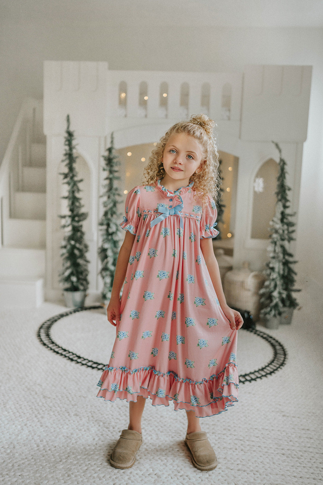 Girl wearing pink floral nightgown with ruffles and blue bows, styled for holiday photos or Christmas morning

Vintage-inspired pink girls nightgown with blue floral print, ruffled hem, and puff sleeves, perfect for winter lounging

Long pink holiday nightgown with double ruffle trim and blue satin bows, ideal for Christmas Eve or heirloom sleepwear