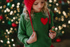 A young girl is wearing an earthy green chenille sweatshirt with a red heart applique on the left chest.  The cozy sweatshirt is sure to grow your heart at least 3 sizes. 