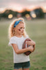 Girl wearing blue “Go Lions” headband holding football on a field at sunset, dressed in white tee and denim shorts

Child wearing sparkly blue team spirit headband that says “Go Lions,” styled with football face sticker and sporty outfit

Little girl showing team pride in “Go Lions” beaded headband while holding football during golden hour on the field

Girls football game day outfit with blue “Go Lions” headband and pigskin, perfect for team spirit wear or cheerleaders