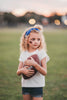 Girl wearing blue “Go Lions” headband holding football on a field at sunset, dressed in white tee and denim shorts

Child wearing sparkly blue team spirit headband that says “Go Lions,” styled with football face sticker and sporty outfit

Little girl showing team pride in “Go Lions” beaded headband while holding football during golden hour on the field

Girls football game day outfit with blue “Go Lions” headband and pigskin, perfect for team spirit wear or cheerleaders