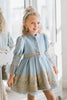 Victorian-inspired blue girls dress with gold embroidery, puff sleeves, and pearl buttons, perfect for birthdays or special occasions

Elegant heirloom girls dress in dusty blue with gold lace trim and tulle layers, hanging on ornate vintage-style mirror

Long sleeve blue and gold embroidered holiday dress for girls, featuring pearl buttons and layered tulle hem