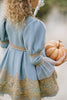 Victorian-inspired blue girls dress with gold embroidery, puff sleeves, and pearl buttons, perfect for birthdays or special occasions

Elegant heirloom girls dress in dusty blue with gold lace trim and tulle layers, hanging on ornate vintage-style mirror

Long sleeve blue and gold embroidered holiday dress for girls, featuring pearl buttons and layered tulle hem