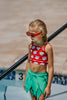 Girls Hawaiian swimsuit with bold red and white monstera top and green layered leaf swim skirt, perfect for beach or resort

Kid's luau-inspired two-piece swimsuit with monstera print top and leafy green skirt, styled with red sunglasses by the pool